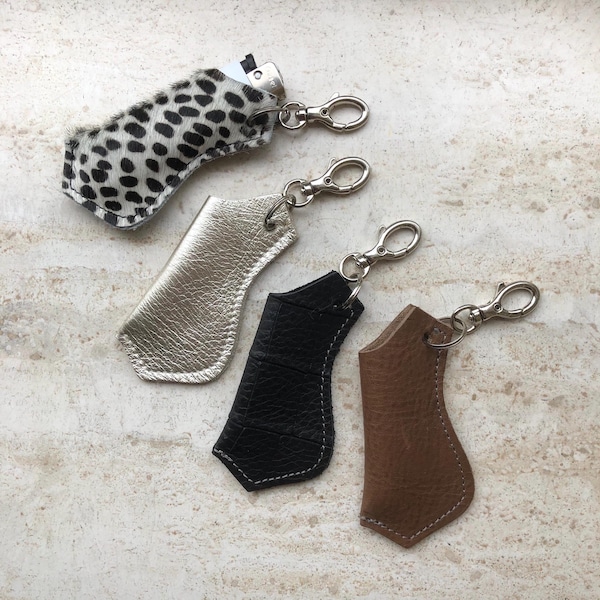 May include: Four lighter cases with silver-tone metal swivel clasps. One case features a black and white spotted animal print texture, one is metallic gold, one is black with a textured finish, and one is brown with a visible white stitch.