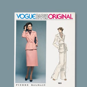 May include: A Vogue Paris Original sewing pattern envelope for a Pierre Balmain design, number 1601. The cover features a photograph of a person wearing a pink belted jacket and matching skirt, alongside a line drawing of the same jacket with trousers.