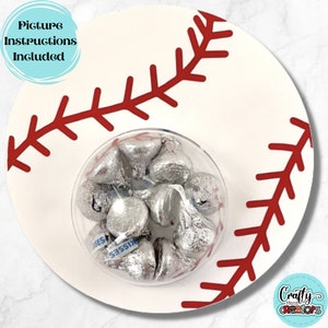 May include: White ceramic plate with a red baseball stitch design. A clear glass bowl filled with silver foil-wrapped chocolate kisses sits in the center of the plate.