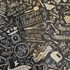 Puede incluir: Tela en blanco y negro con temática de cocina, con texto e ilustraciones manuscritos. El diseño incluye frases como «Receta para la amistad», «Hornear con amor» e imágenes de utensilios de cocina como batidores y tazas medidoras.