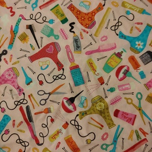 Op de afbeelding: Een lichtroze stof met een herhaald patroon van kappersgereedschap. Het ontwerp omvat haardrogers, scharen, kammen, haarspray en producttubes. De tekst op de tubes bevat "blonde", "red", "Spritz", "black" en "toner".