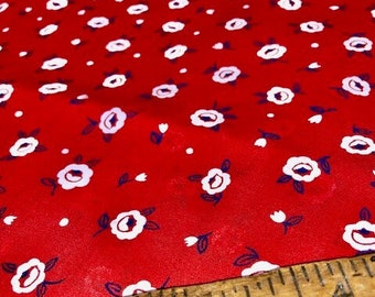 May include: Red fabric with a white floral pattern. A wooden ruler with the text "Complete Furnishings" is placed on top of the fabric.