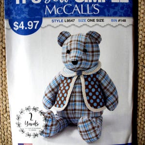 May include: A McCall's sewing pattern envelope for a stuffed bear, labeled IT'S SEW SIMPLE, style L9547. The image shows a seated bear made from blue and brown plaid fabric, wearing a brown vest with blue polka dots and a cream-colored lace trim.