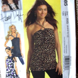 May include: A McCall's M5585 sewing pattern envelope featuring a leopard print halter top with a circular neck ring. The packaging displays illustrations of three different top variations, including a solid black version and a purple floral print.