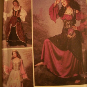 May include: A costume pattern featuring three different medieval or Renaissance-style dresses. The dresses are in shades of red, black, and white, with details like lace, corsets, and flowing sleeves. The pattern is from Wrights and Simplicity Trims.