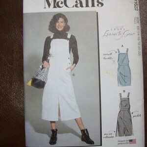 May include: A McCall's sewing pattern featuring a woman wearing a white overall dress. The pattern includes illustrations of the dress and instructions for sewing. The text reads "Learn to Sew" and "Designed and printed in USA."
