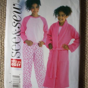 May include: A See & Sew B4322 sewing pattern envelope featuring illustrations of a two-piece pajama set with a light pink raglan sleeve top and patterned pants, and a solid pink robe. The text includes B4322, See & Sew, and YES! IT'S EASY.