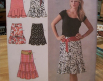 Simplicity 3881 Missses (Size H5 6,8,10,12,14) and (R5 14,16,18,20,22) skirt with flounce and length variations and belt. FF, uncut