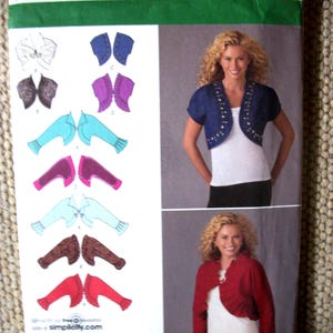 May include: A Simplicity sewing pattern envelope 2478 for bolero jackets in sizes H5 6, 8, 10, 12, 14. The front displays illustrations of various sleeve and trim styles, alongside photographs of a blue embellished bolero and a red ruffled bolero.