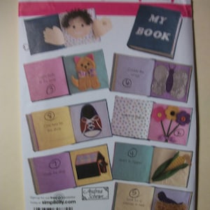 May include: A Simplicity pattern for a fabric book with various colorful pages. The pages feature felt appliqués of a doll, dog, shoe, flowers, and other objects. The cover of the book reads "MY BOOK".