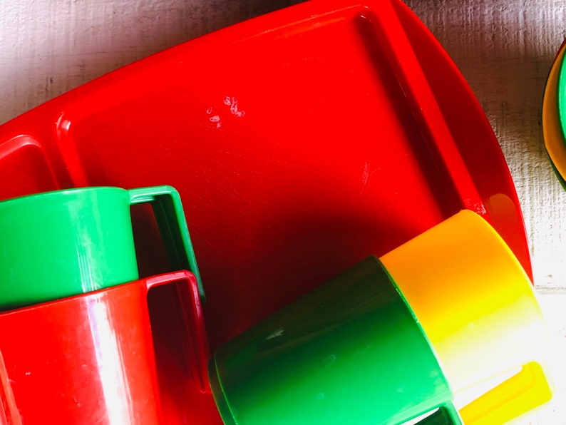 Puede incluir: Una bandeja de pl&aacute;stico roja con tres vasos de pl&aacute;stico de colores. Los vasos son verdes, rojos y amarillos. Los vasos tienen asas.
