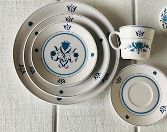 May include: A set of three white ceramic plates with a blue floral design. The plates are nested together and have a blue rim. There is also a matching blue and white teacup and saucer.