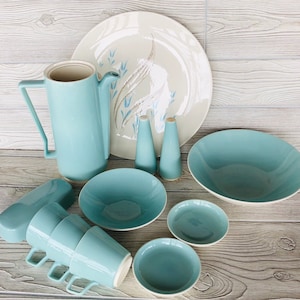 May include: A set of light blue ceramic dishes, including a large serving bowl, a platter with a white and blue floral design, four cups, a creamer, a sugar bowl, and two salt and pepper shakers.