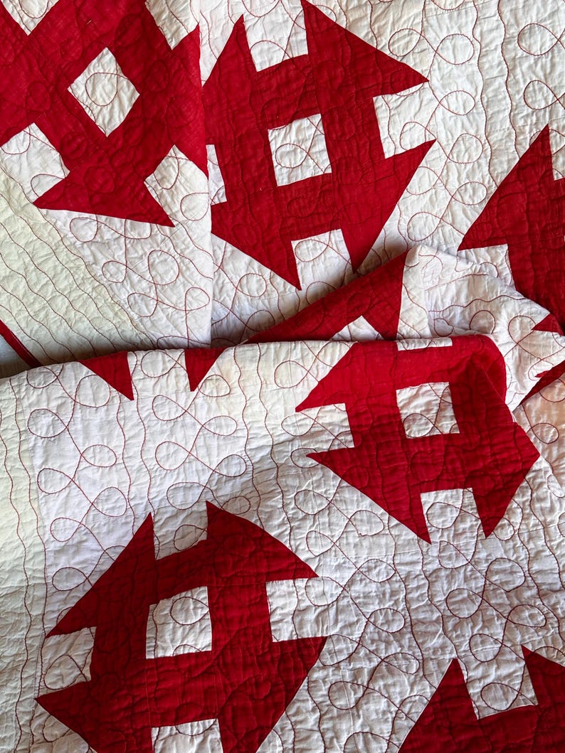 Peut inclure: Gros plan sur une courtepointe faite &agrave; la main avec un motif r&eacute;p&eacute;titif de formes g&eacute;om&eacute;triques rouges sur un fond blanc. La courtepointe est cousue avec du fil rouge, cr&eacute;ant une surface textur&eacute;e. Le design est de style classique et traditionnel.