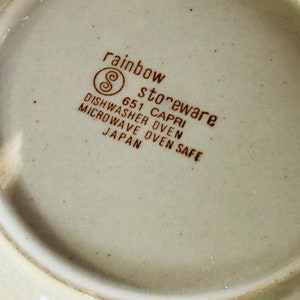 Może przedstawiać: Zbliżenie na sp&oacute;d białego ceramicznego talerza z brązowym tekstem, kt&oacute;ry brzmi "rainbow stoneware 651 CAPRI DISHWASHER OVEN MICROWAVE OVEN SAFE JAPAN".