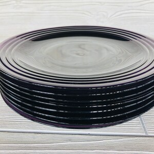 May include: A stack of eight black glass dinner plates with a subtle iridescent sheen.
