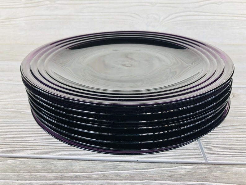 May include: A stack of eight black glass dinner plates with a subtle iridescent sheen.
