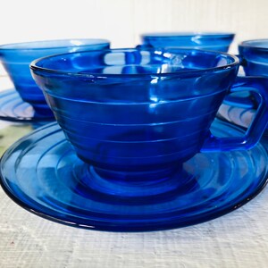 May include: Set of four cobalt blue glass teacups and saucers. The cups and saucers have a fluted design.