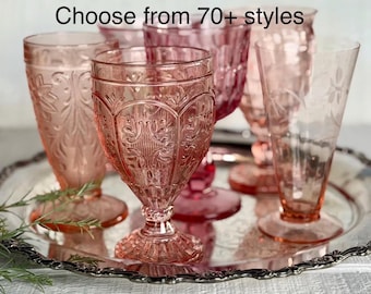 May include: A collection of pink glass goblets and glasses with various embossed patterns and etched designs, arranged on a silver tray. The text "Choose from 70+ styles" is visible at the top of the image, showcasing multiple glassware options.