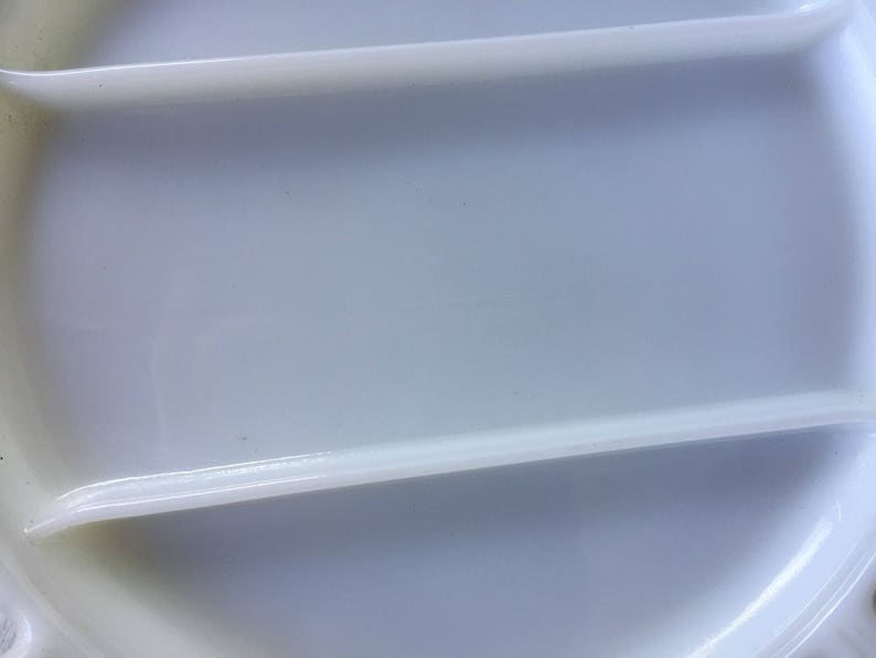 May include: A white plastic lid with two raised ridges. The lid is smooth and has a slight sheen.