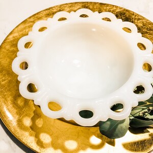 May include: A white milk glass bowl with a scalloped edge and a gold charger plate underneath.