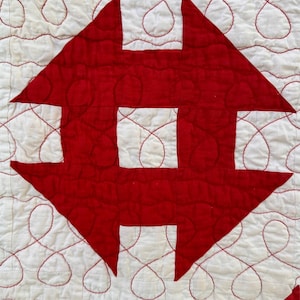 Peut inclure: Gros plan sur un textile matelass&eacute; avec un motif r&eacute;p&eacute;titif de formes g&eacute;om&eacute;triques rouges sur fond blanc. Les formes rouges sont cousues sur le tissu blanc, avec du fil rouge soulignant les formes et cr&eacute;ant un motif d&eacute;coratif.