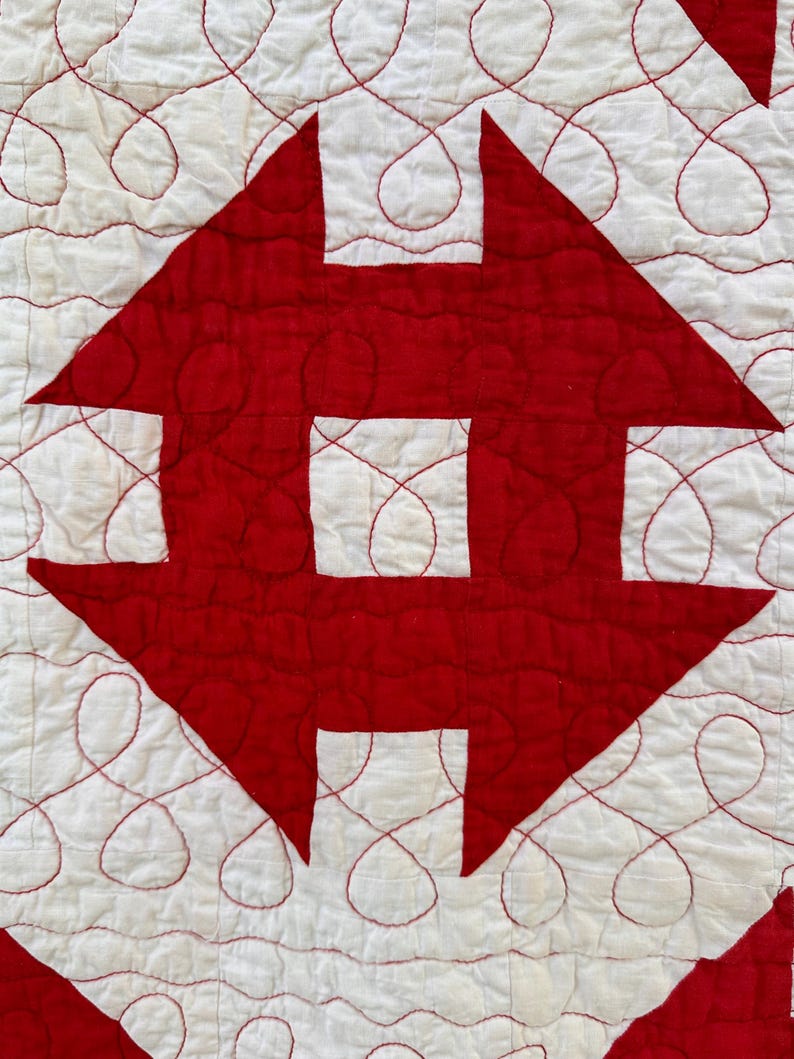 Peut inclure: Gros plan sur un textile matelass&eacute; avec un motif r&eacute;p&eacute;titif de formes g&eacute;om&eacute;triques rouges sur fond blanc. Les formes rouges sont cousues sur le tissu blanc, avec du fil rouge soulignant les formes et cr&eacute;ant un motif d&eacute;coratif.