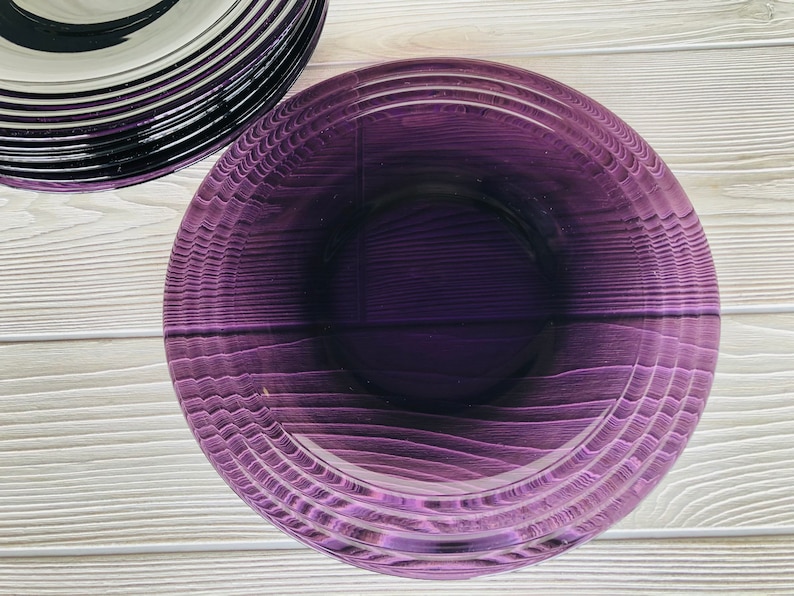 May include: A purple glass bowl with a textured, rippled design. The bowl is empty and has a glossy finish.