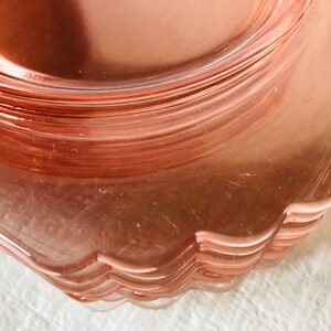 May include: A stack of pink glass dessert plates with scalloped edges.