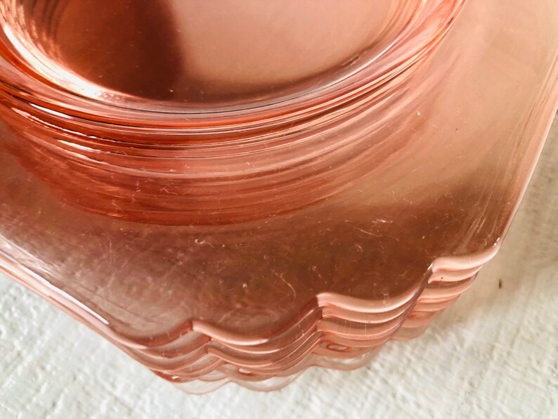 May include: A stack of pink glass dessert plates with scalloped edges.