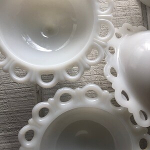 May include: Three white milk glass bowls with scalloped edges. The bowls are nested together, with the largest bowl on the bottom and the smallest bowl on top.