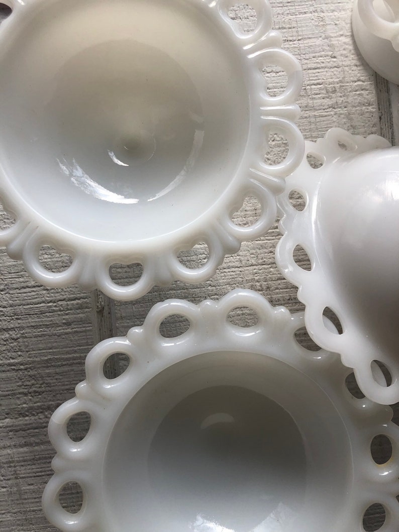 May include: Three white milk glass bowls with scalloped edges. The bowls are nested together, with the largest bowl on the bottom and the smallest bowl on top.