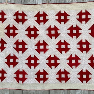 Peut inclure: Une courtepointe faite &agrave; la main avec un motif r&eacute;p&eacute;titif de formes g&eacute;om&eacute;triques rouges sur un fond cr&egrave;me. La courtepointe a une bordure rouge. Le design est sym&eacute;trique et les coutures sont visibles. Fabriqu&eacute; en coton.