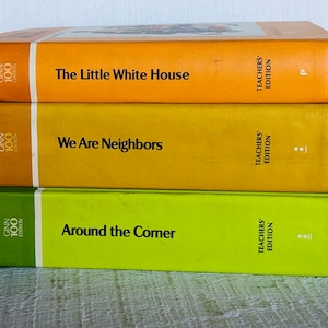 May include: Three vintage books stacked on top of each other. The top book is orange and titled "The Little White House." The middle book is yellow and titled "We Are Neighbors." The bottom book is green and titled "Around the Corner."