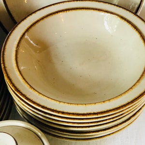 Może przedstawiać: Stos beżowych ceramicznych misek z brązową obw&oacute;dką. Miski są włożone jedna w drugą i mają kropkowaną glazurę.