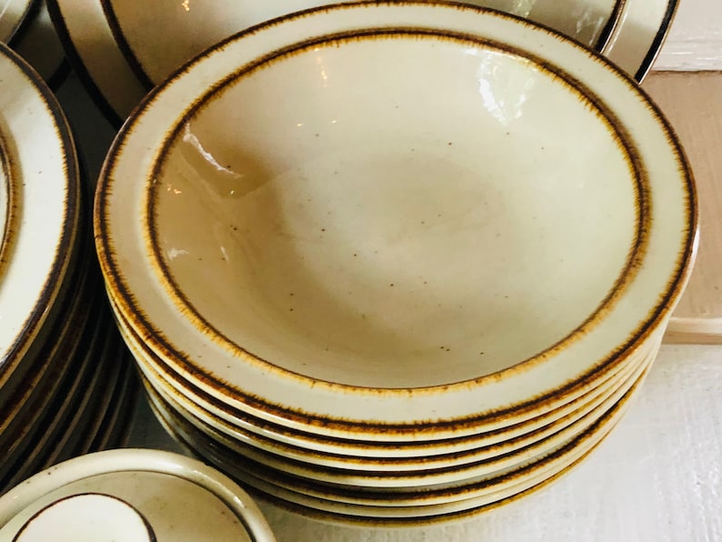 Może przedstawiać: Stos beżowych ceramicznych misek z brązową obw&oacute;dką. Miski są włożone jedna w drugą i mają kropkowaną glazurę.