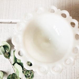 May include: A white milk glass bowl with a scalloped edge and a ring design around the rim. The bowl is empty and has a glossy finish.