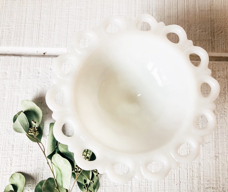 May include: A white milk glass bowl with a scalloped edge and a ring design around the rim. The bowl is empty and has a glossy finish.