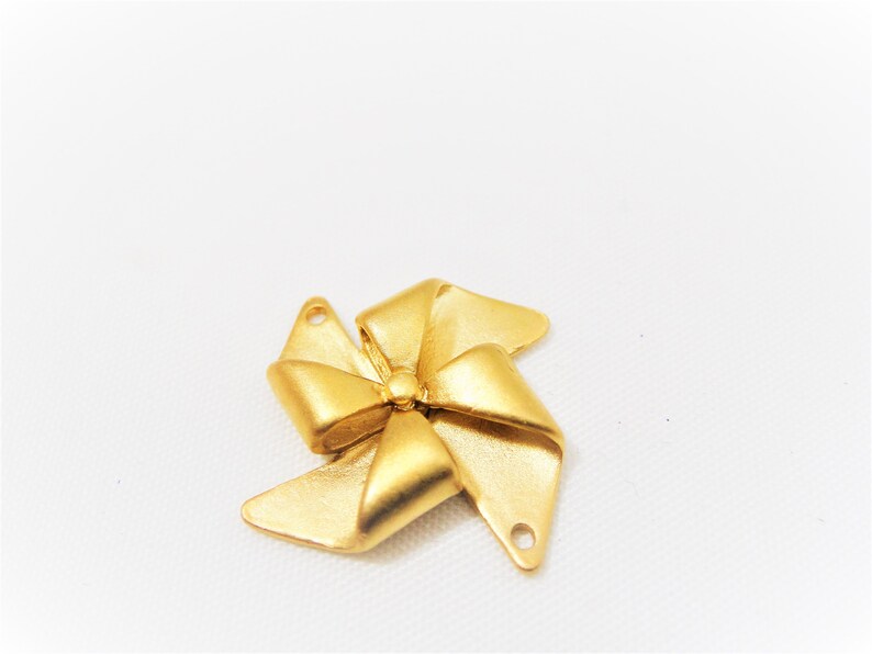 May include: A gold-colored metal bow charm with two holes for attaching to jewelry or other crafts.