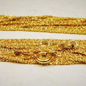 May include: A gold chain necklace with a delicate, textured design. The chain is layered and features a lobster clasp closure.