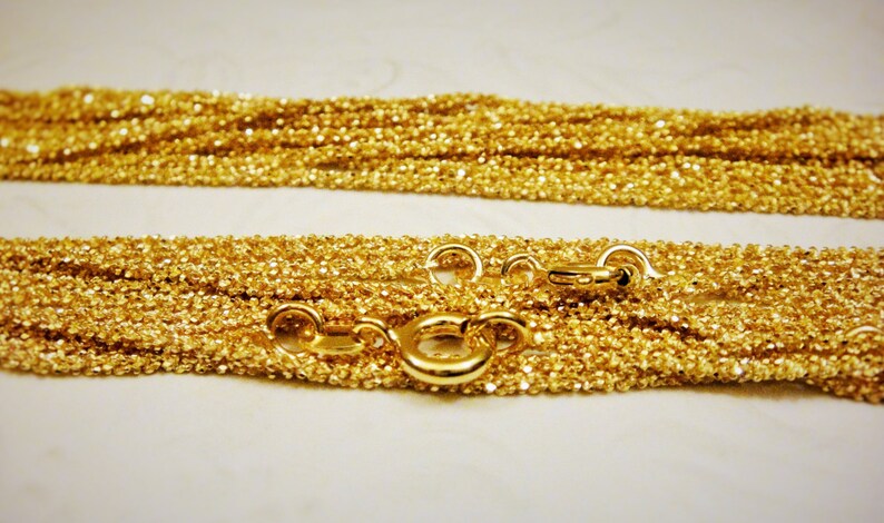May include: A gold chain necklace with a delicate, textured design. The chain is layered and features a lobster clasp closure.
