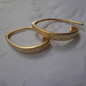 Könnte beinhalten: Ein Paar goldfarbene, gehämmerte quadratische Creolen. Die Ohrringe sind schlicht und elegant und würden eine großartige Ergänzung für jede Schmucksammlung sein.