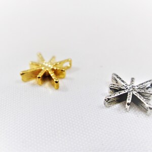 May include: Two star-shaped charms, one gold and one silver, with a textured surface.