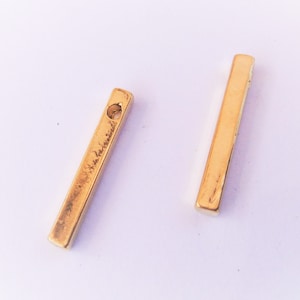 May include: Two gold-colored metal bar connectors with a hole in the center of each bar.