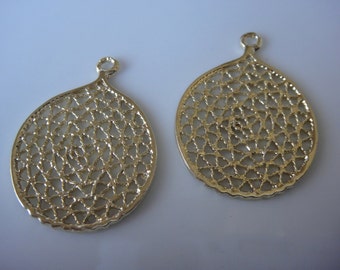 May include: Two gold-toned metal pendant charms with a delicate, intricate, circular, filigree design. The charms have a loop at the top for attaching to jewellery.