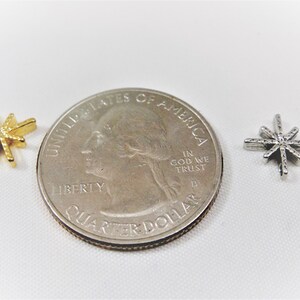 May include: Two star-shaped charms, one gold and one silver, are shown next to a US quarter to show their size.