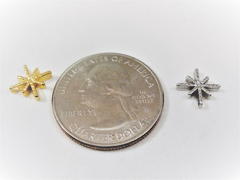 May include: Two star-shaped charms, one gold and one silver, are shown next to a US quarter to show their size.
