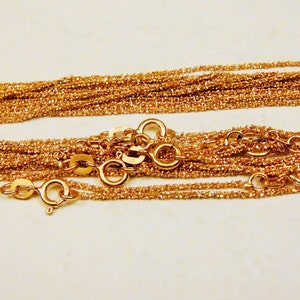 Puede incluir: Primer plano de un mont&oacute;n de collares de cadena de color dorado con m&uacute;ltiples cierres.