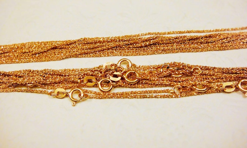 Puede incluir: Primer plano de un mont&oacute;n de collares de cadena de color dorado con m&uacute;ltiples cierres.