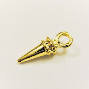 May include: A gold-colored metal charm shaped like a pointed cone with a decorative ring at the top.
